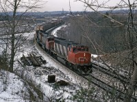 Four axle GMD locomotives CN 9448 (GP40-2LW), CN 5576 (GP38-2W), and CN 9540 lead an Extra east through CN Hamilton West at fractional mileage on the Dundas sub, near the bottom of the grade from Copetown.<br><br> 
The gap in the trees where the photographer stood has grown in, but good views remain steps ahead. In 2019 the far part of the CP "S" curve and bridge over CN are obscured, jointed rails are not stockpiled for this main line, and westbound Dundas sub signals are down at Bayview.<br><br>
CN 5576 was renumbered to CN 4776 in 1988; it was seen switching railcars in Aldershot Yard on several dates in 2017 in the current www.cn.ca paint scheme.
